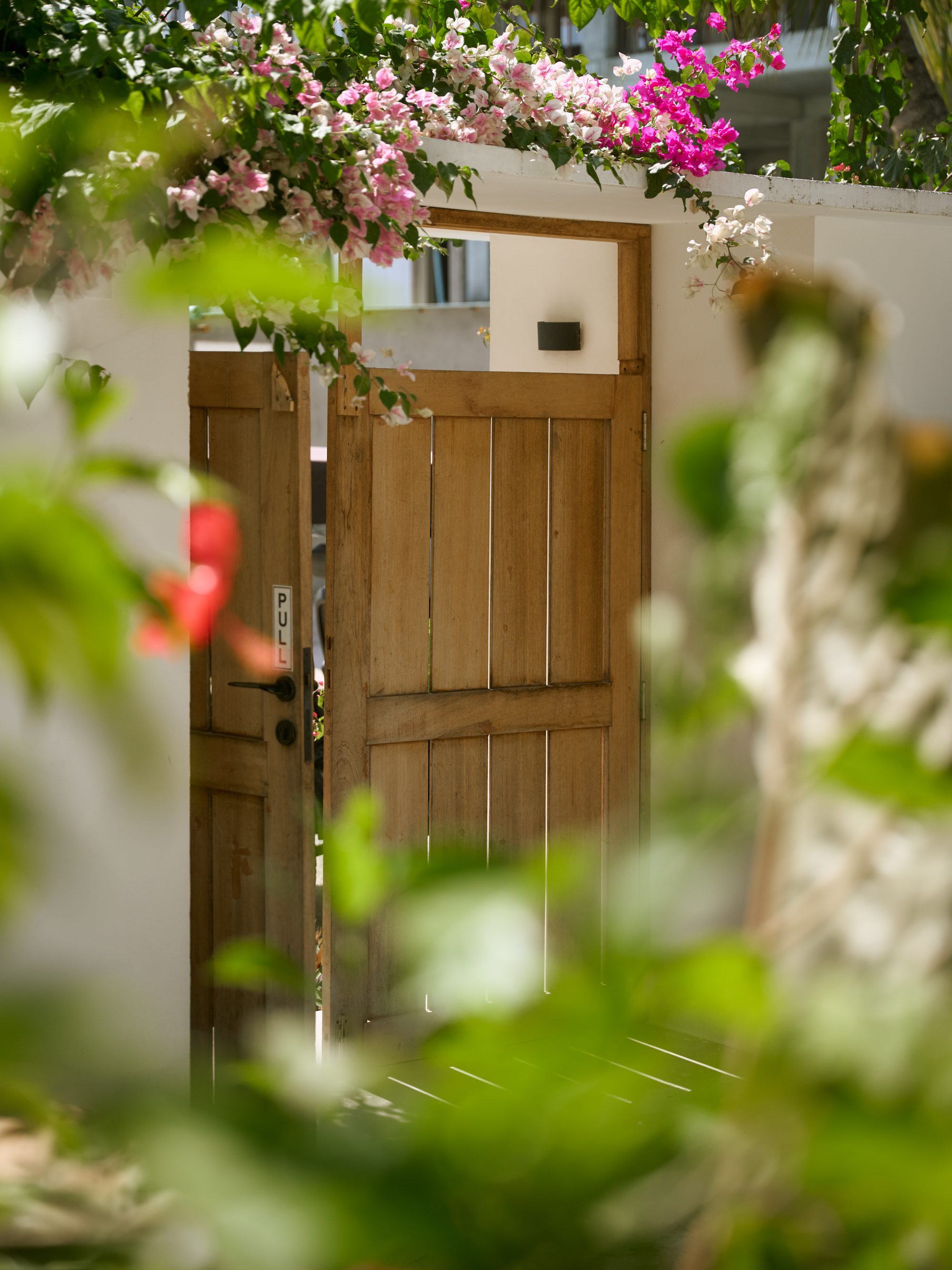 La puerta de madera del jardín enmarcada por buganvillas
