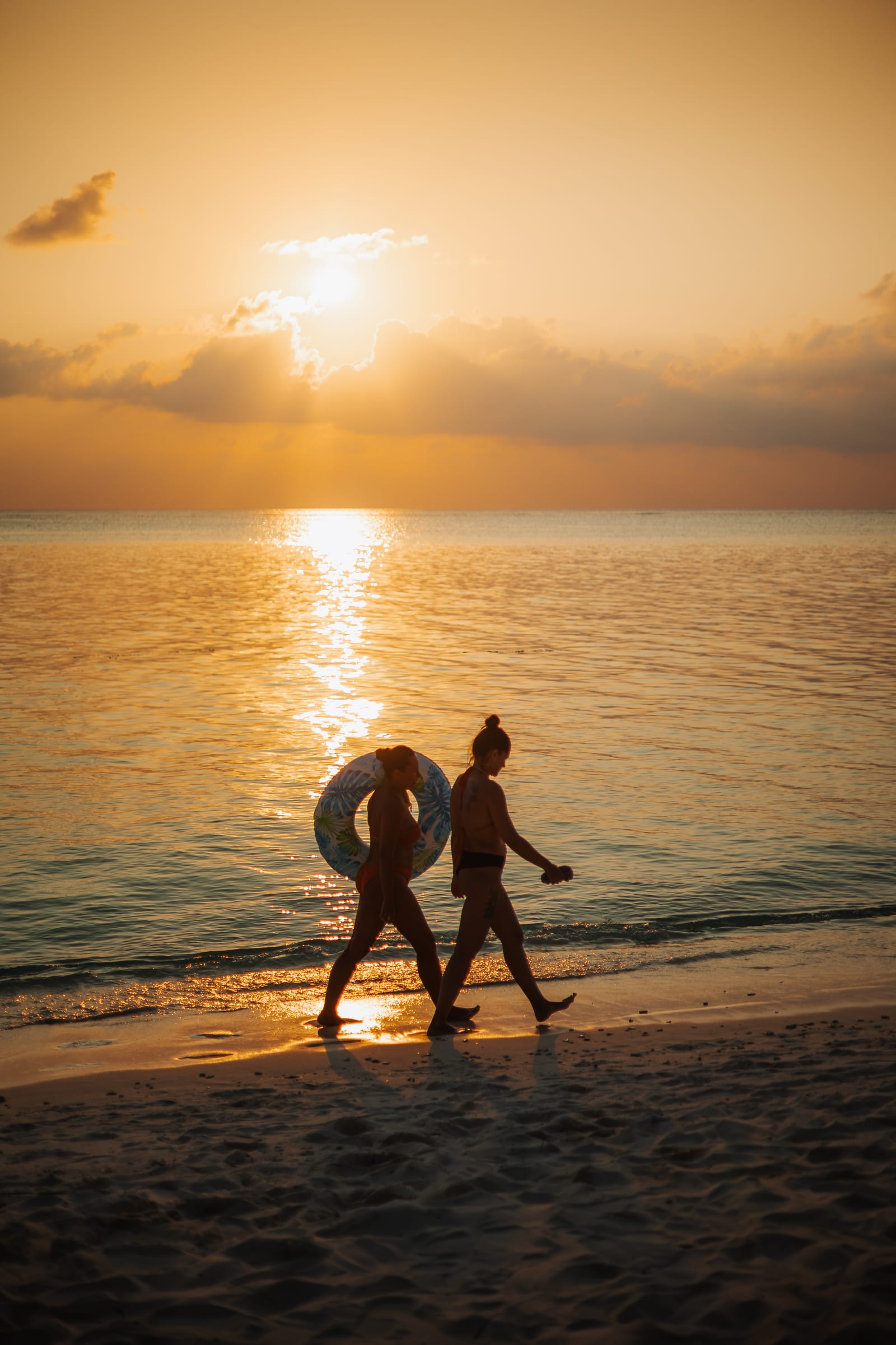 Two Belena guests walking a quiet Thoddoo beach at golden hour