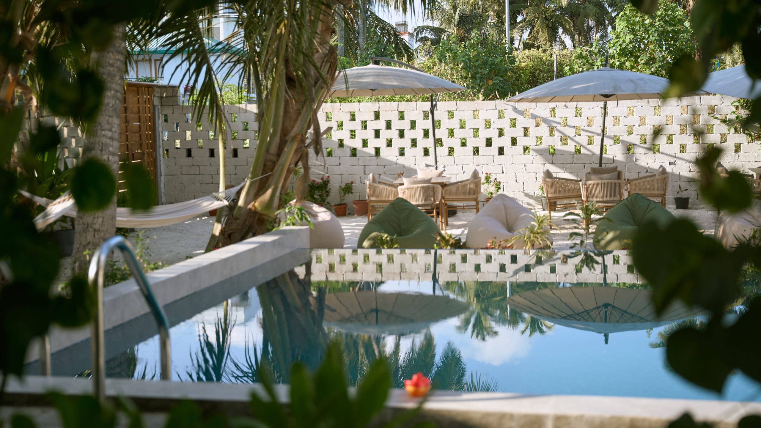 La piscina y sus tumbonas, vistas a través del jardín
